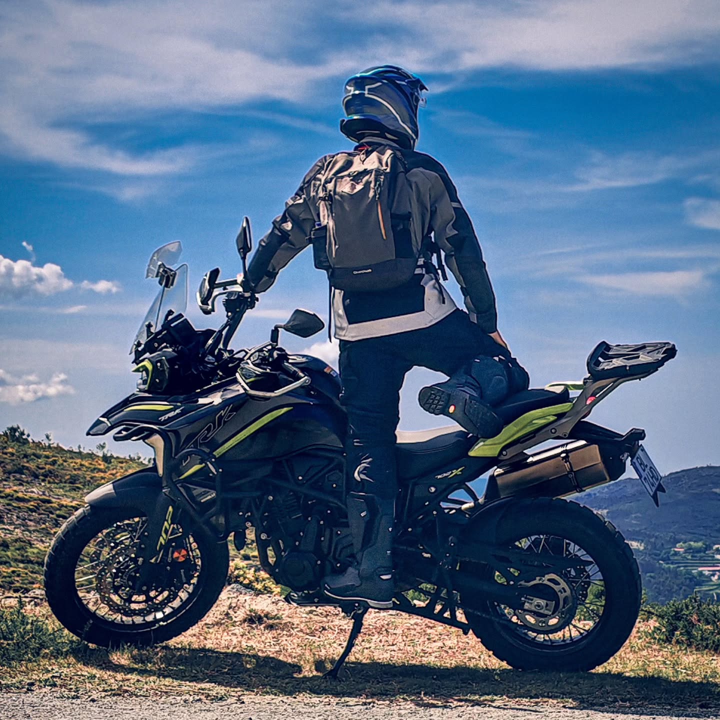Motorcycle rider standing by bike on a scenic hilltop